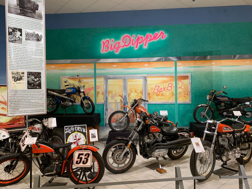 Collection of classic motorcylces in front of a backdrop of a classic diner called "Big Dippers"