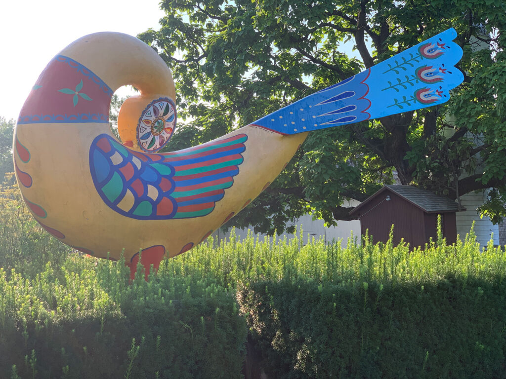 folk art statue of a bird painted yellow with blue wings and tail