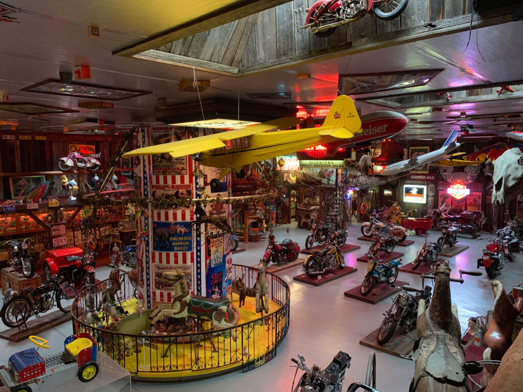 A small yellow glider hangs in a room filled with rows of motorcycles and an antique carousel ride at Bill's Old Bike Barn