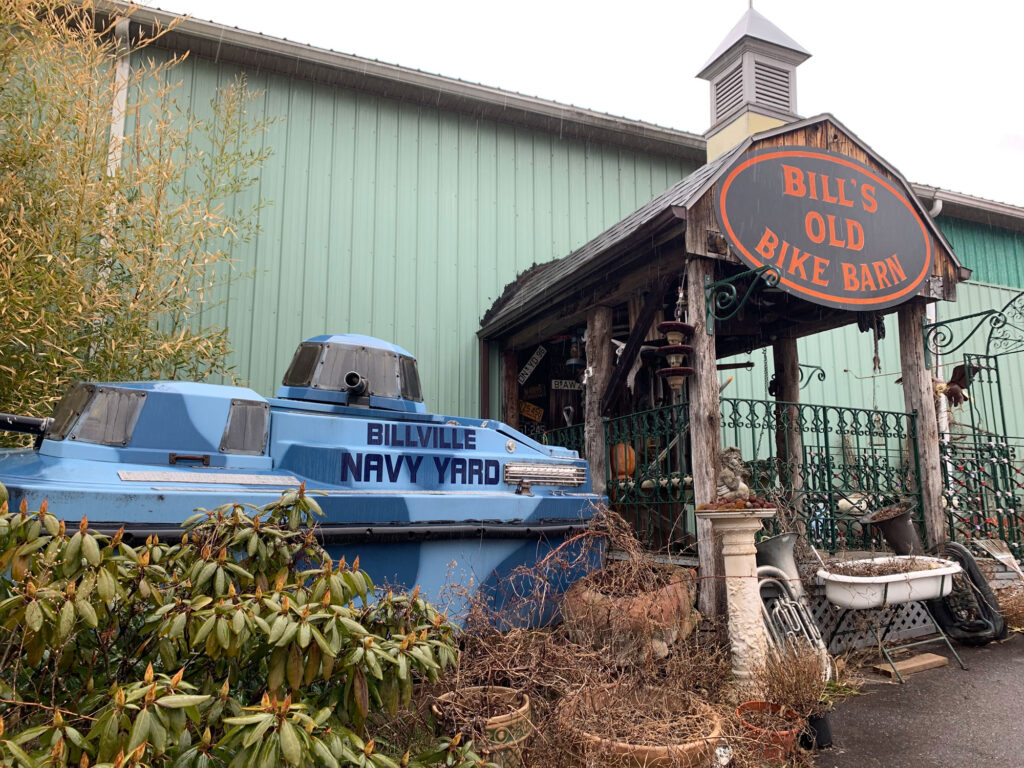 Entrance to a green warehouse with a sign above the door that says Bill's Old Bike Barn