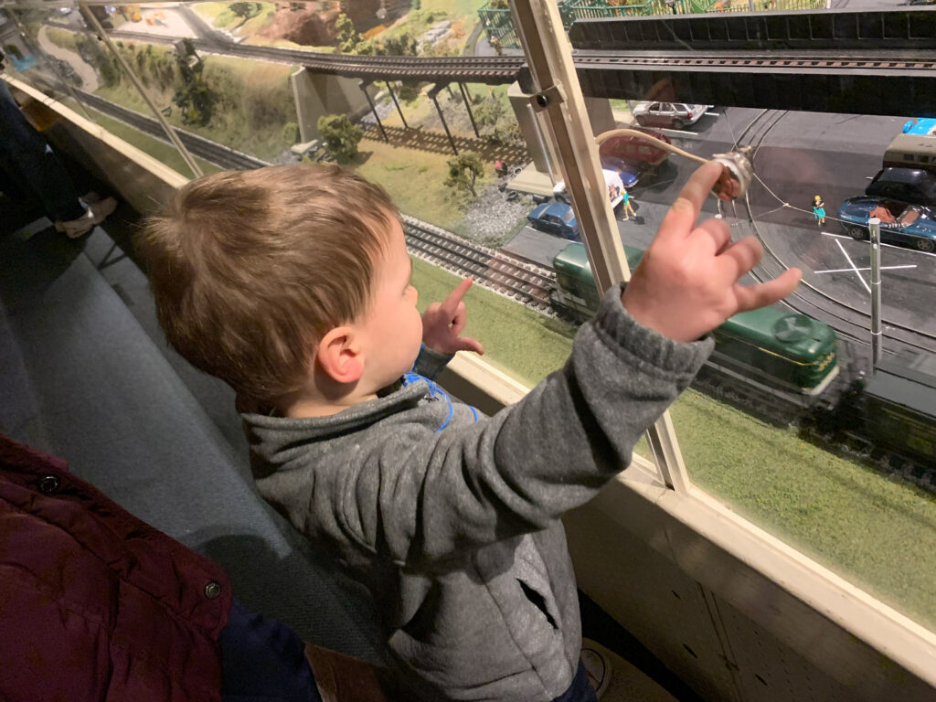 young child looks through the glass at the model layout at the Choo Choo Barn