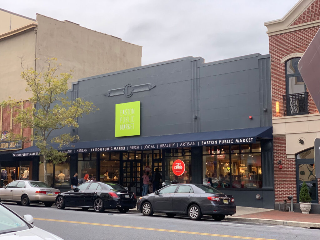 Building with black facade and a bright green sign that reads "Easton Public Market"