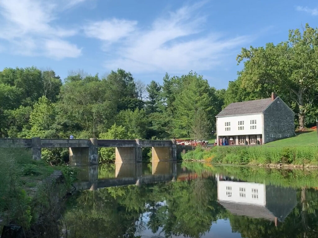 Stone bridge over water leads to a white barn at Gring's Mill in Reading, PA