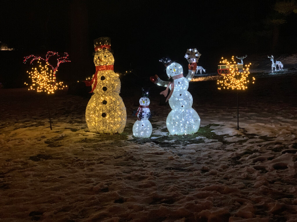 Lighted snowmen sit in a snowy area at the Holiday Lights at Gring's Mill