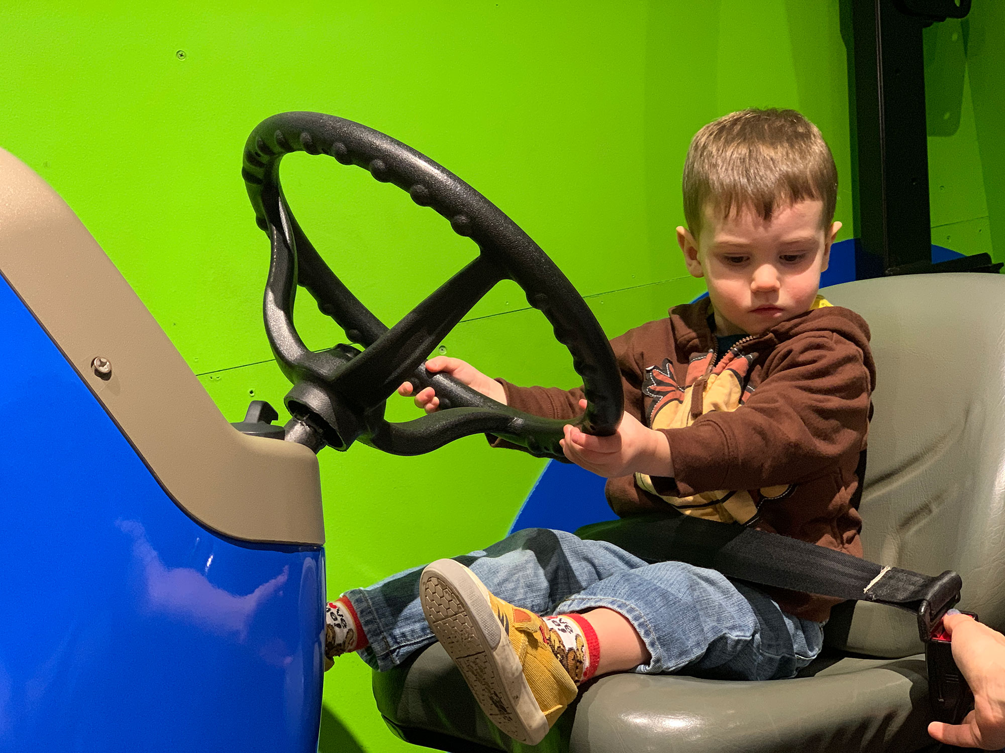 young child sitting on a blue tractor at the Hands-On House in Lancaster, PA