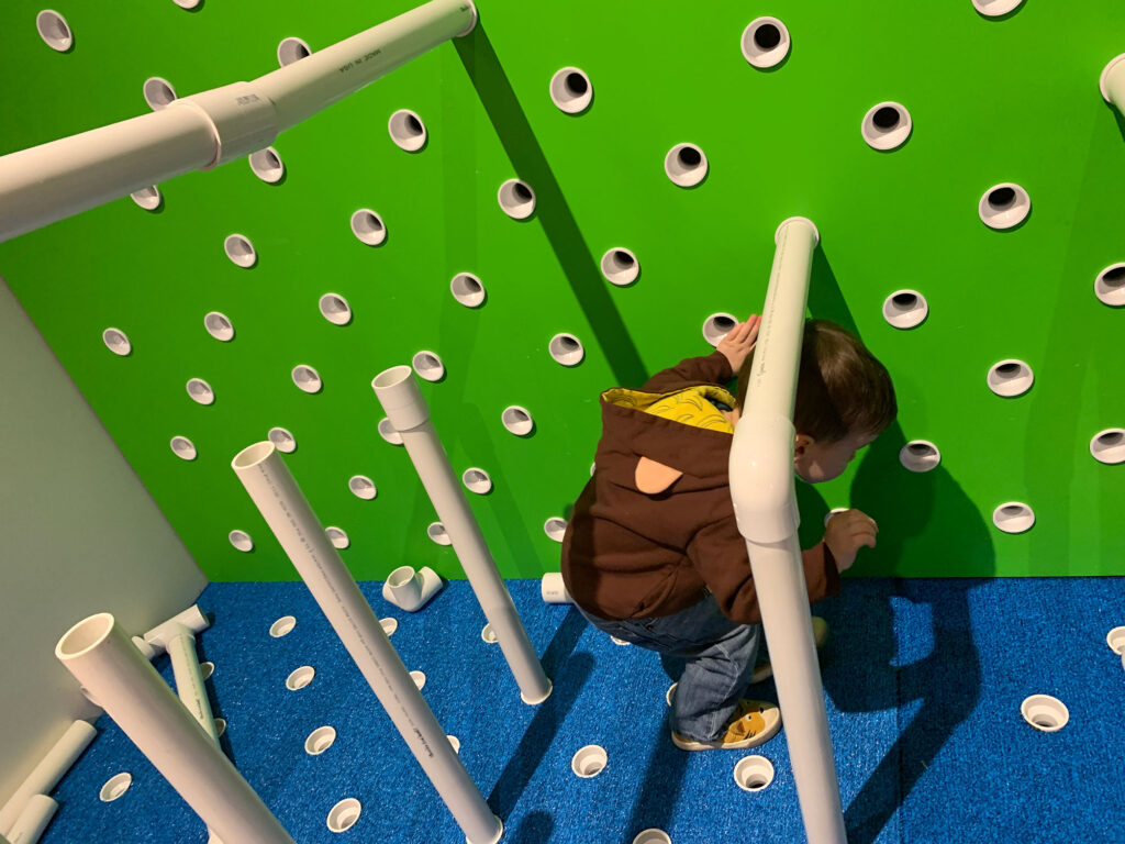 child playing amongst PVC pipes at the Hands-On House