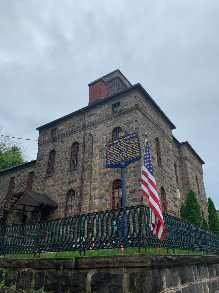 Large stone building with historic marker in front telling the history of the Old Jail in JIm Thorpe