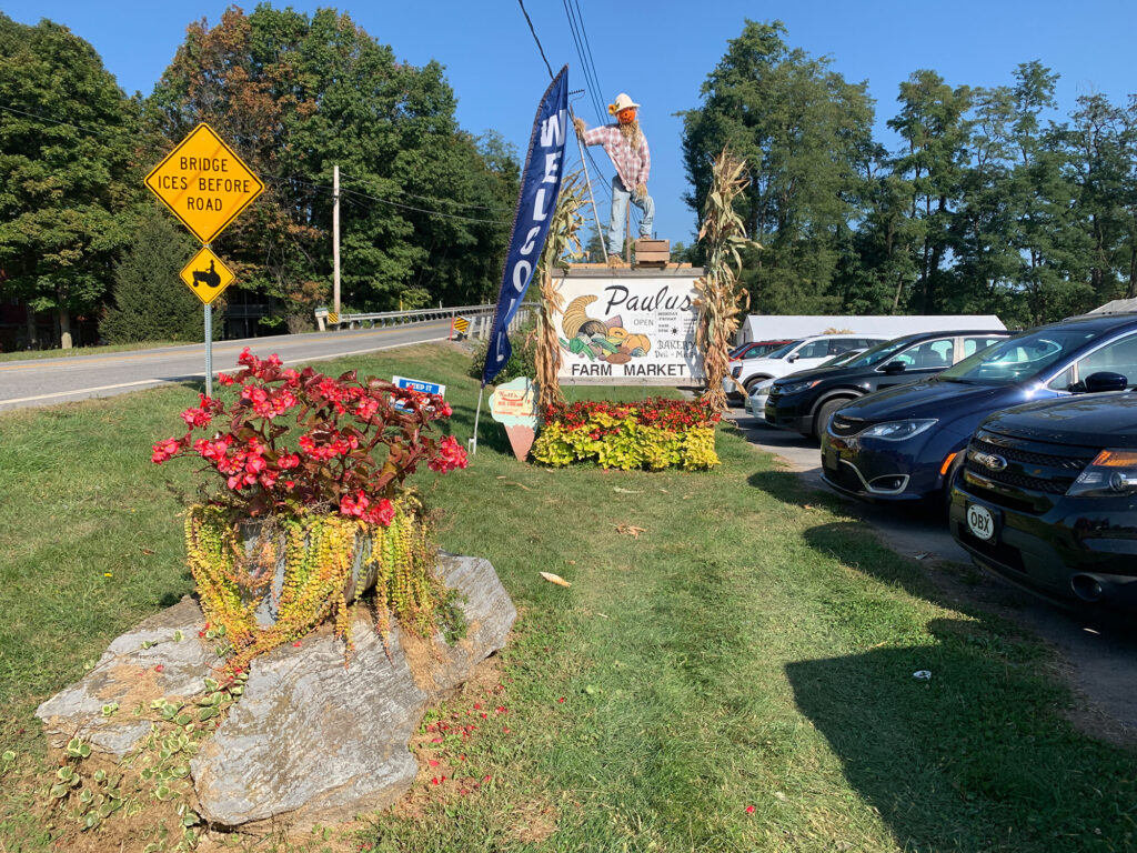 sign for Paulus Farm Market decorated with fall corn husks and a scarecrow