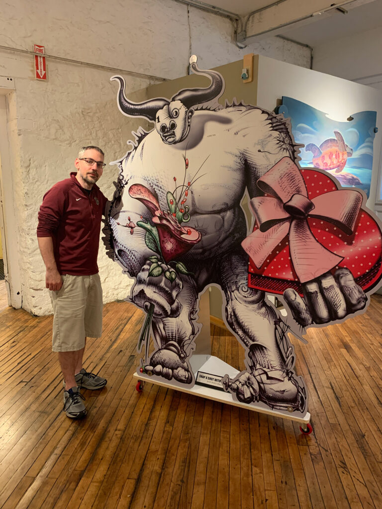 Man posing for a picture with a cardboard cutout of a half-man half-bull