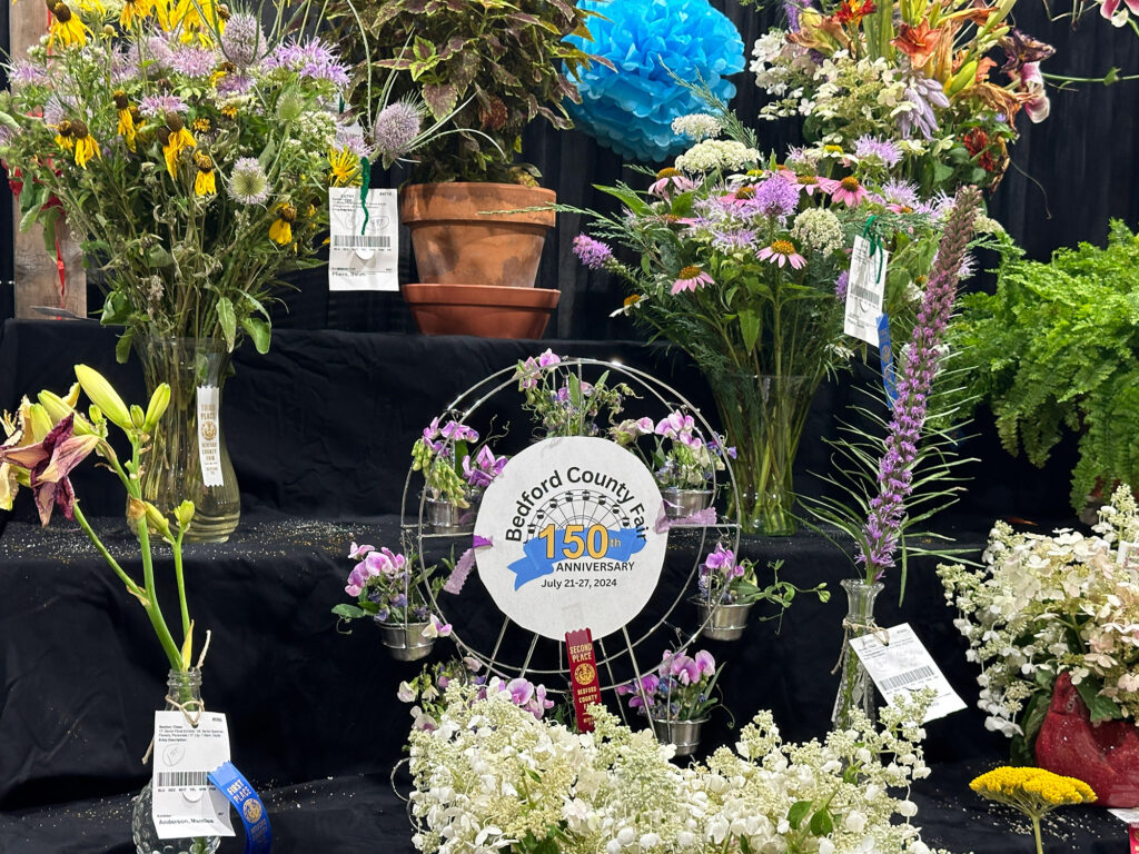 floral display with a Bedford County Fair 150th anniversary logo in the center