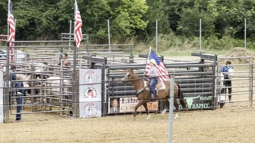 woman riding a horse carrying the American flag before a rodeo competition at the Berks County Fair