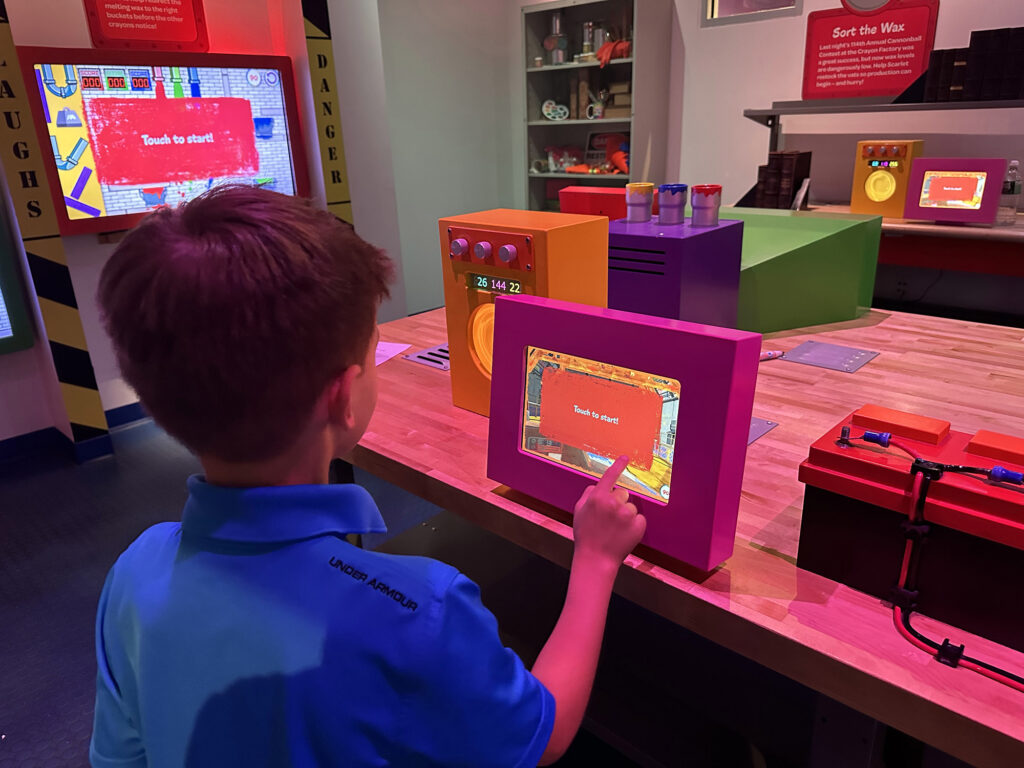 child playing on a video screen inside Crayola Experience