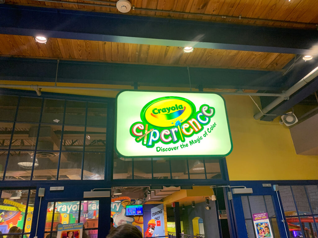 lit sign with "Crayola Experience" in bright colors above the entrance to the attraction