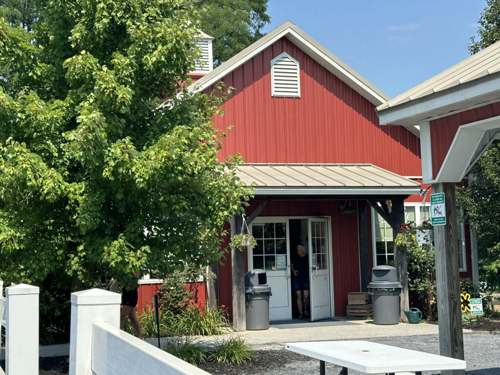 Red barn-shaped building with someone walking out of a white door