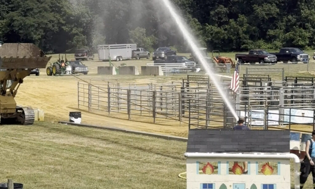 firefighter sprays a hose at a bulldozer during the firefighter competiton at the Lebanon Fair