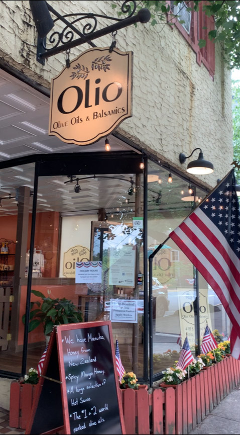 storefront with a round sign reading "Olio Olive Oils and Balsamics"