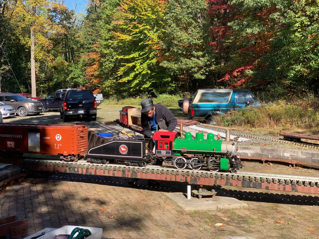 man working on an outdoor model steam engine