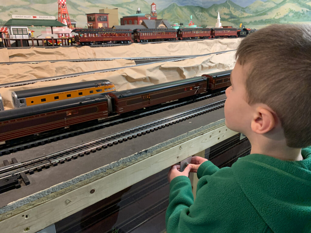 young boy looking at a model train set