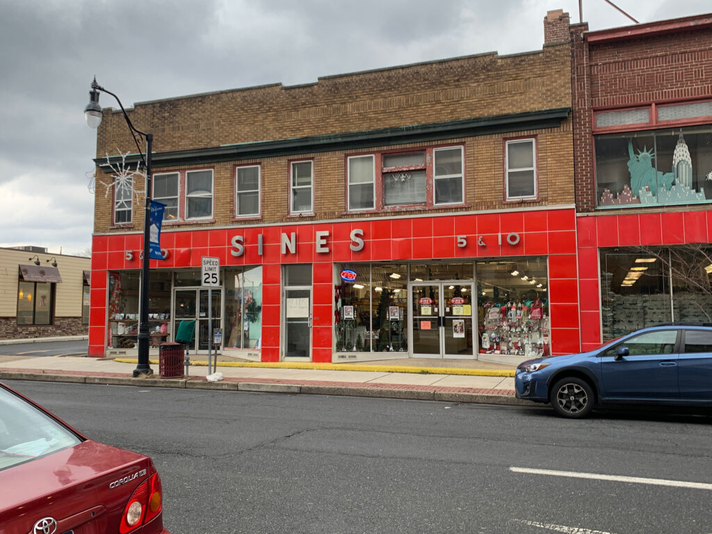 Brick building with a red facade over the first floor and white letters reading Sine's 5 & 10