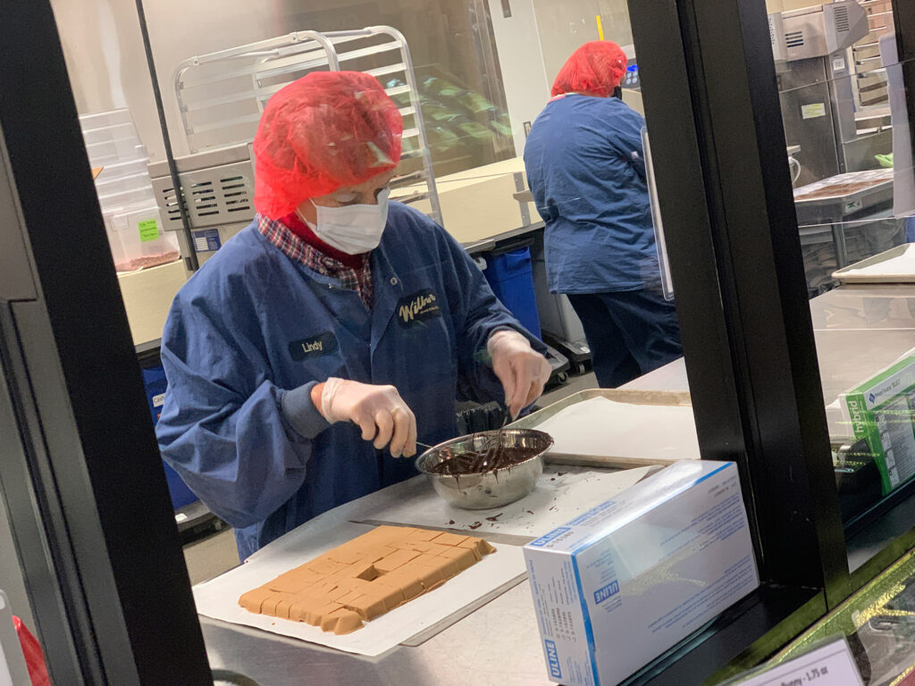 woman dipping spoon into chocolate at the Wilbur Chocolate store in Lititz, PA