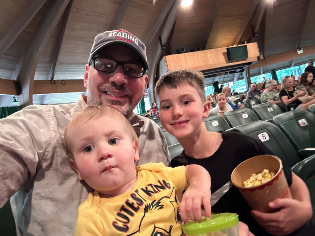 father with two young boys inside an open-air theatre