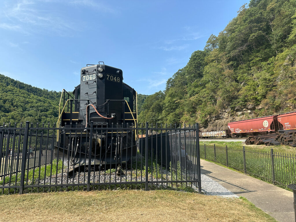 freight cars pass the former Pennsylvania Railroad diesel engine #739 on display at Horseshoe Curve