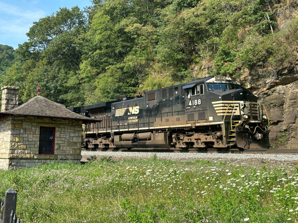 Norfolk Southern diesel passing a small brick shed at the Horseshoe Curve