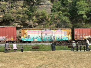 yellow boxcar graffitied with the word "Met" in large bubble letters that fade from red to blue 