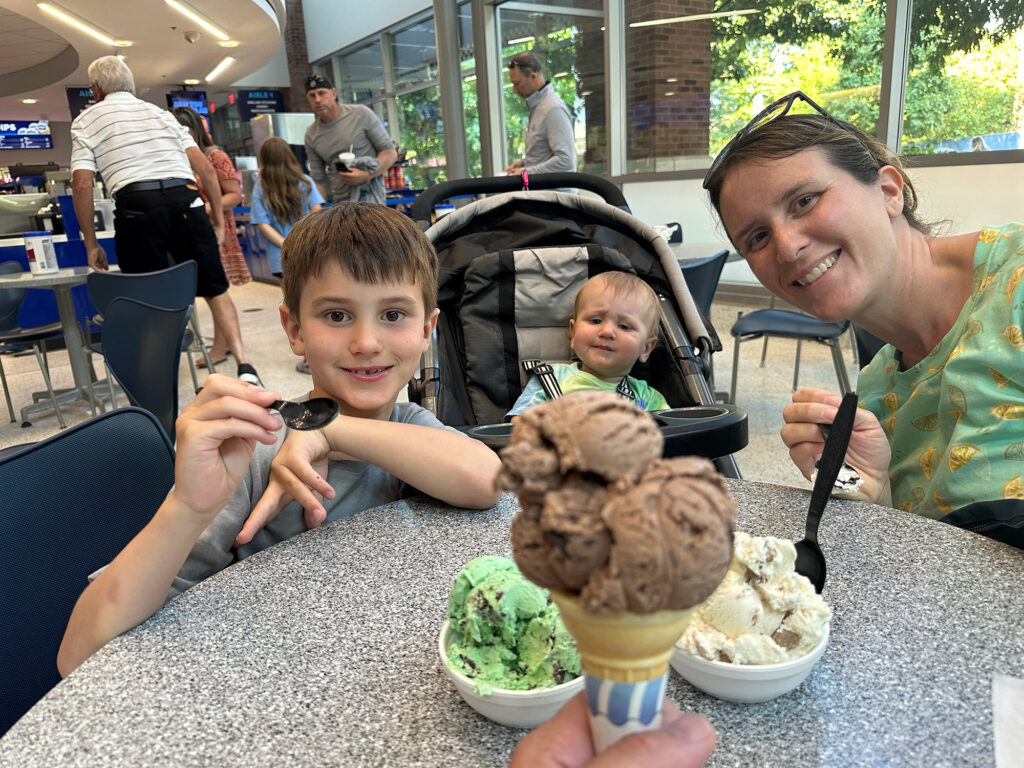 mother with young son and a toddler in a stroller showing off their ice cream