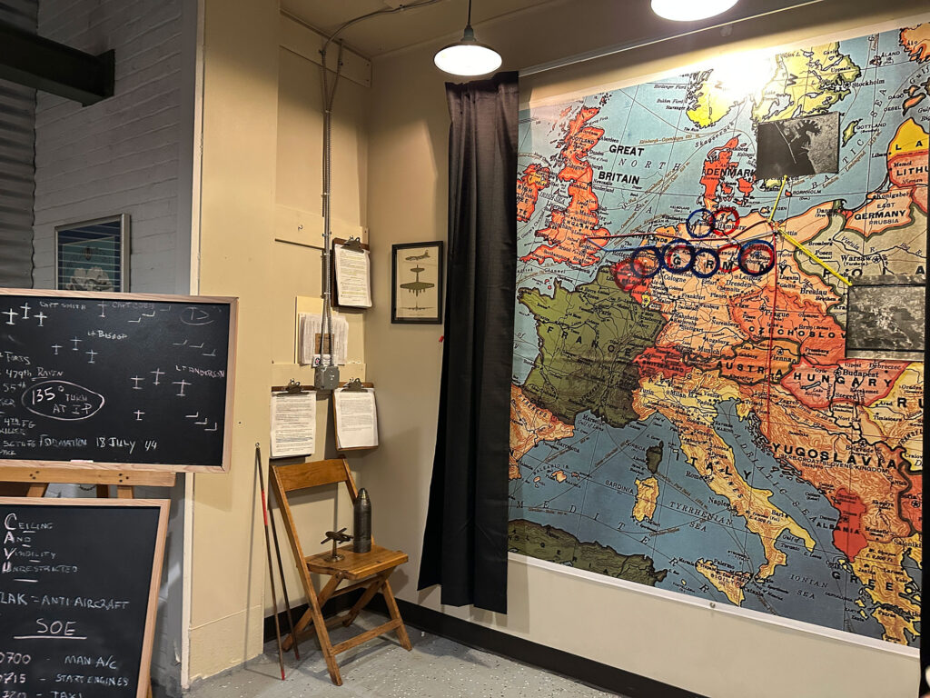 replica riefing room with a map on the wall with cicled targets and a blackboard with code