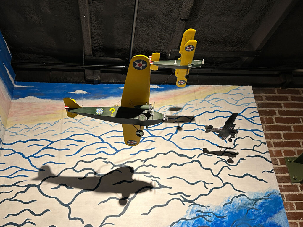 two model 1920s planes in yellow and olive green hanging from the ceiling