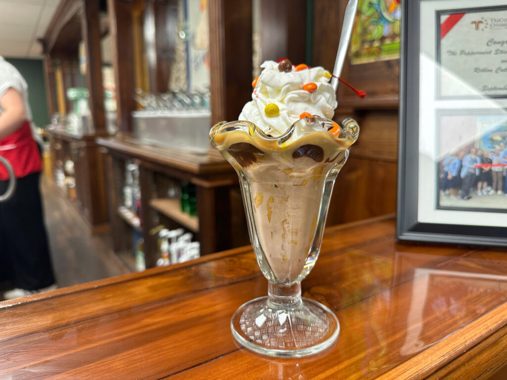 ice cream sundae on a wooden counter in front of an old fashioned soda fountain