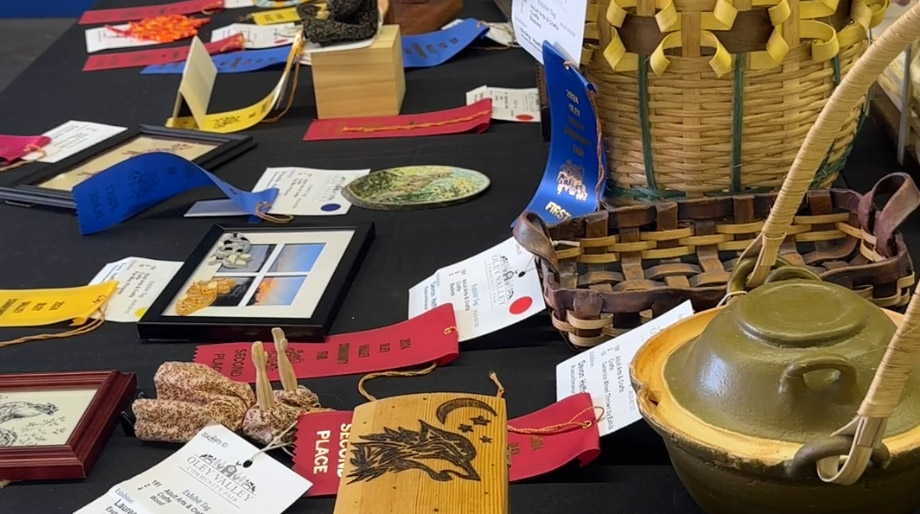 a wicker basket and variou shandmade items on a table with red and blue ribbons denoting fair winners