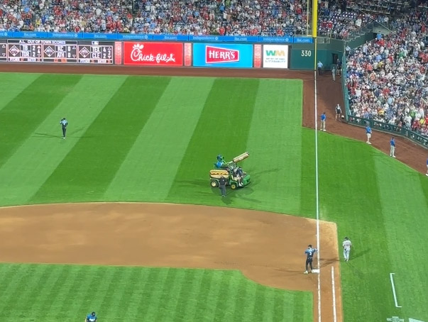 Phillie Phanatic riding an ATV with a hot dog-shaped launcher to shoot hot dogs into the stands