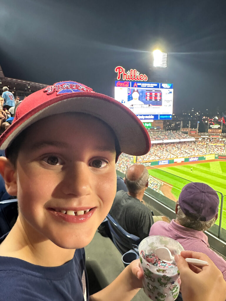 young boy smiling at the camera while holding a cup of Dippin' Dots ice cream