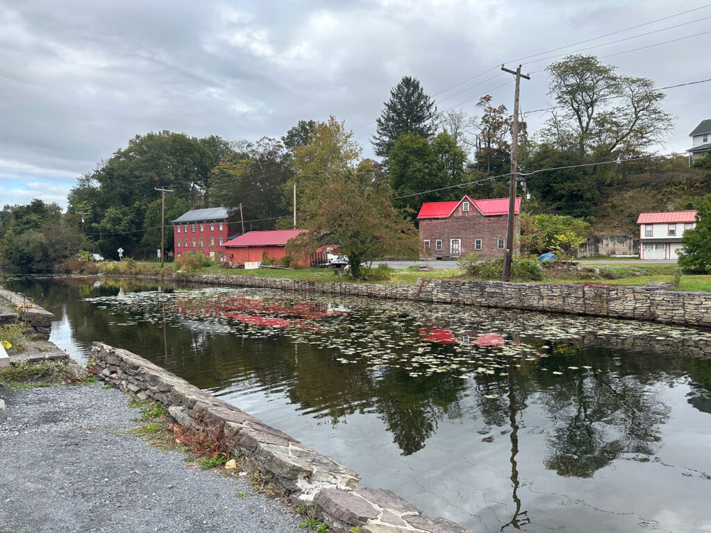 canal with still water reflecting the red roofs of the stone buildings across the street.