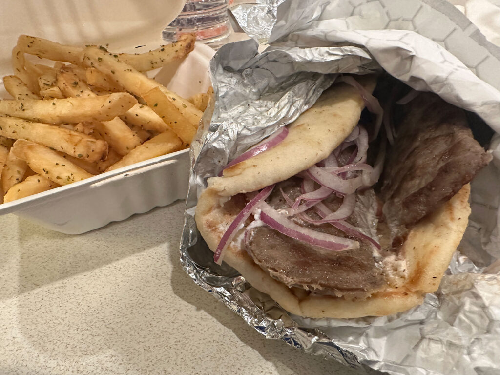 Gyro in aluminum foil next to a styrofoam clamshell filled with fries from the Greek Food Bazaar in Reading, PA.