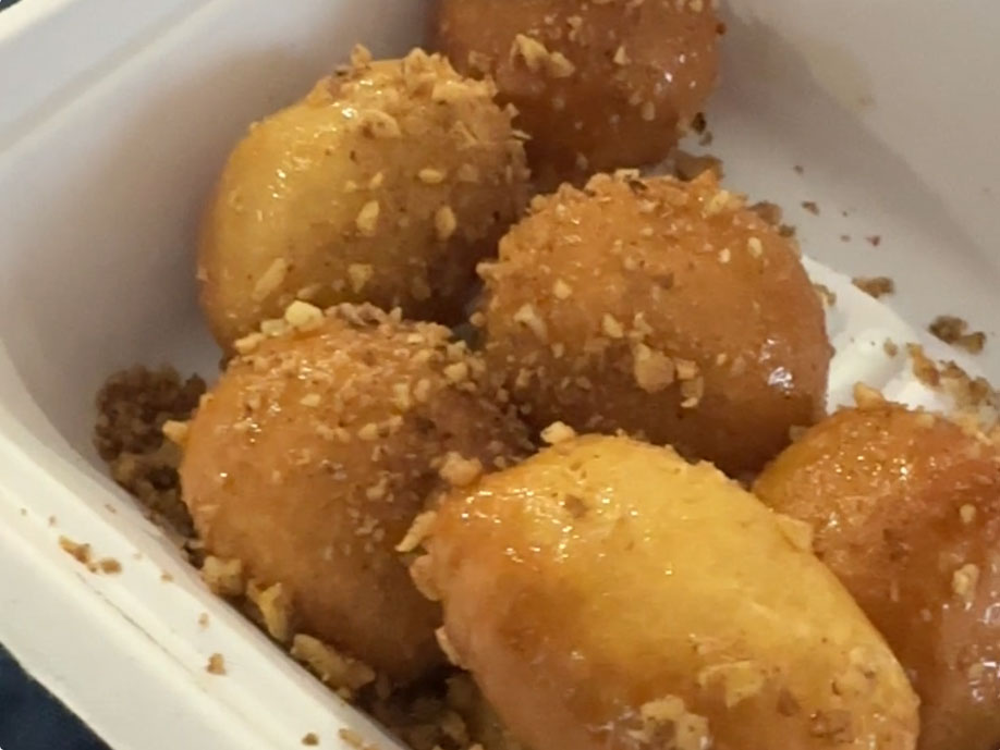 styrofoam container with six donut holes rolled in honey and almonds.