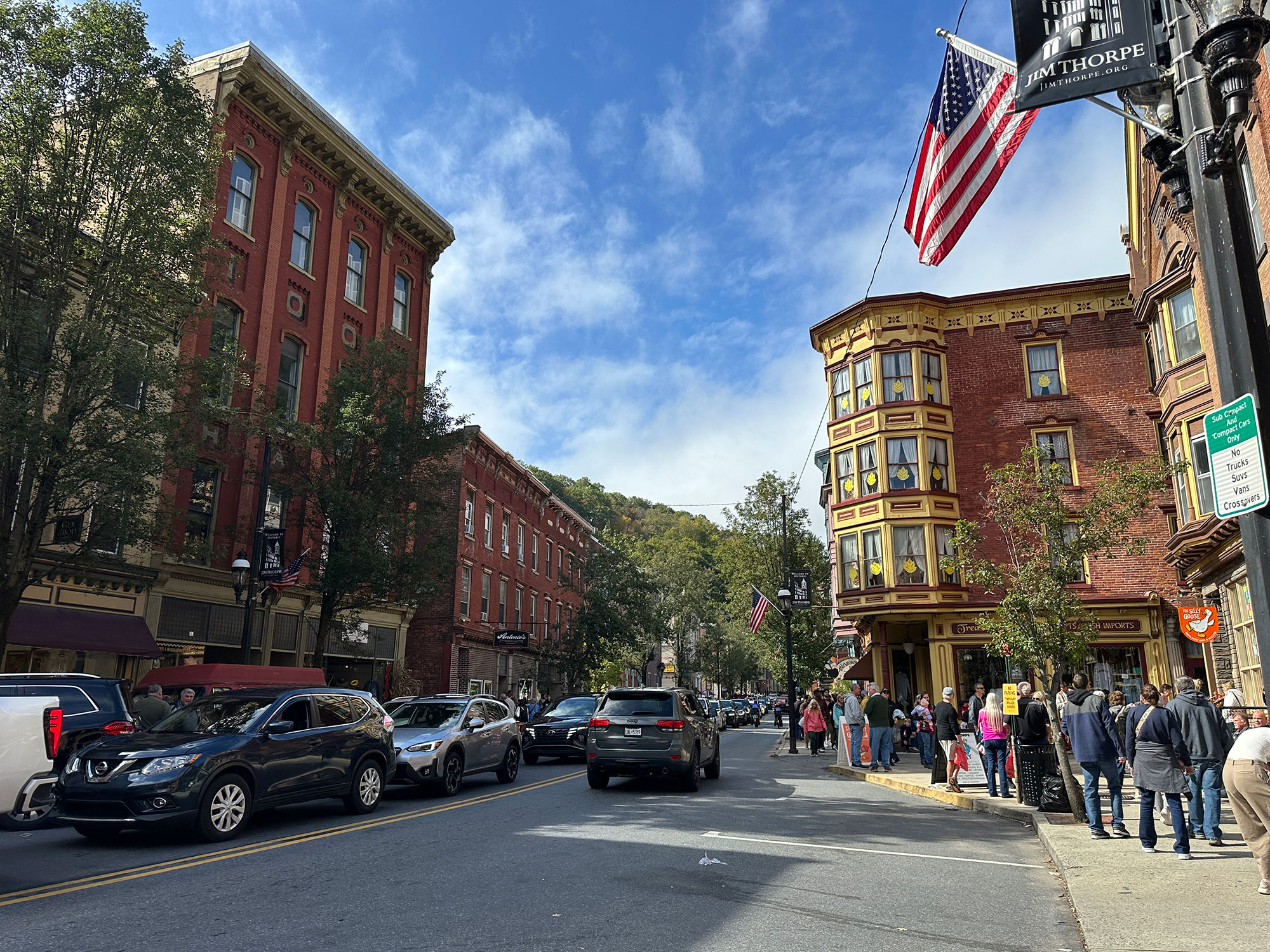 American flag hangs from a storefront with Victorian-era buildings behind it and across the street