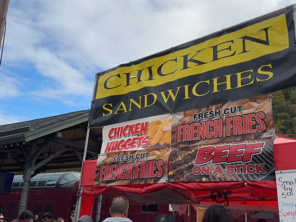A large sign reading "Chicken, Sandwiches" hangs above a food tent at the Jim Thorpe Fall Foliage Festival.