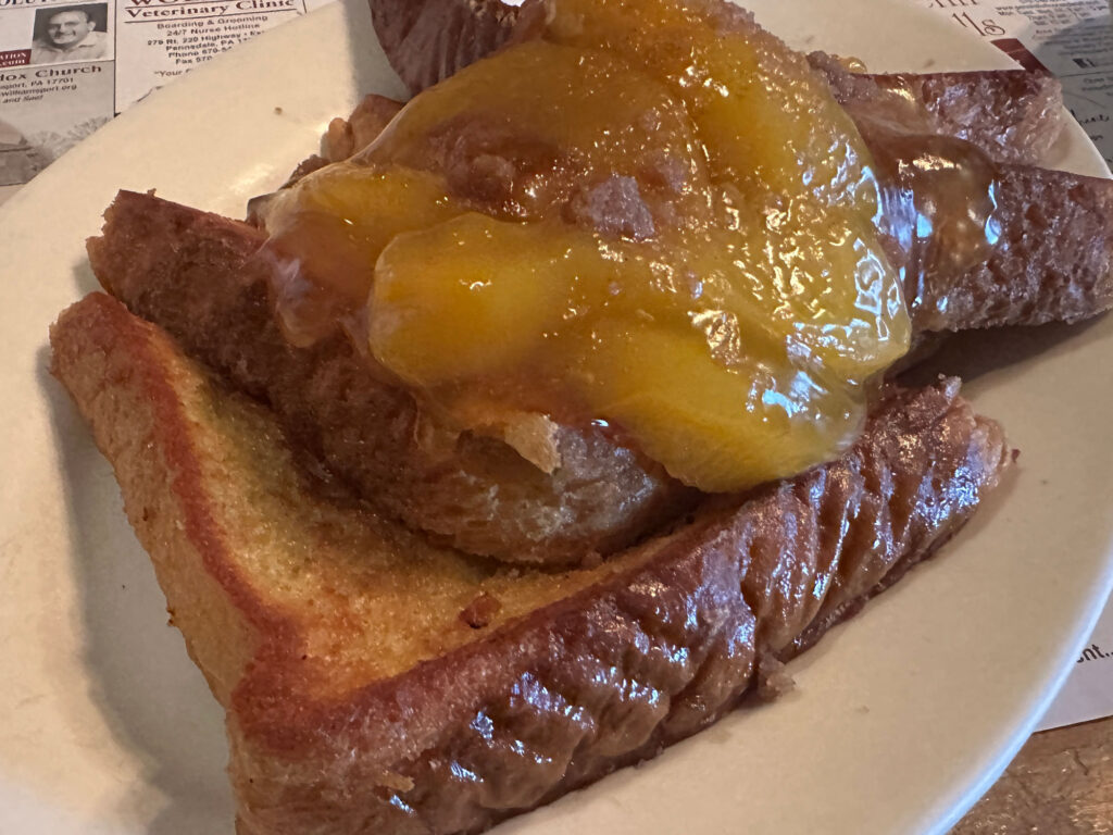 plate with four triangular slices of French toast topped with peach pie filling.
