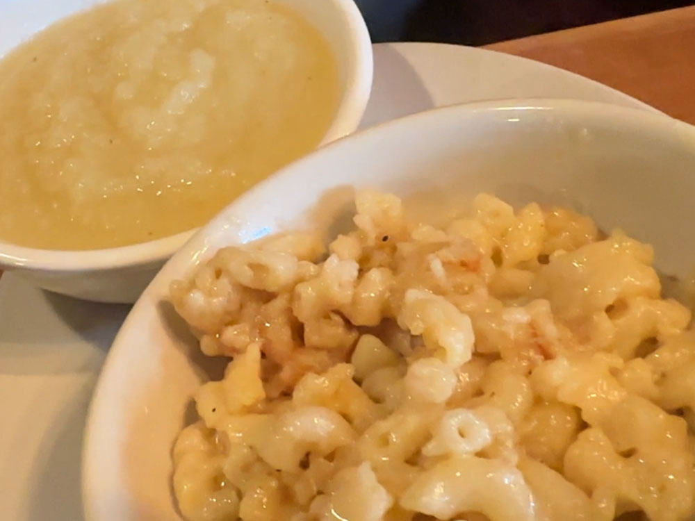 a bowl of mac and cheese next to a smaller bowl of applesuace