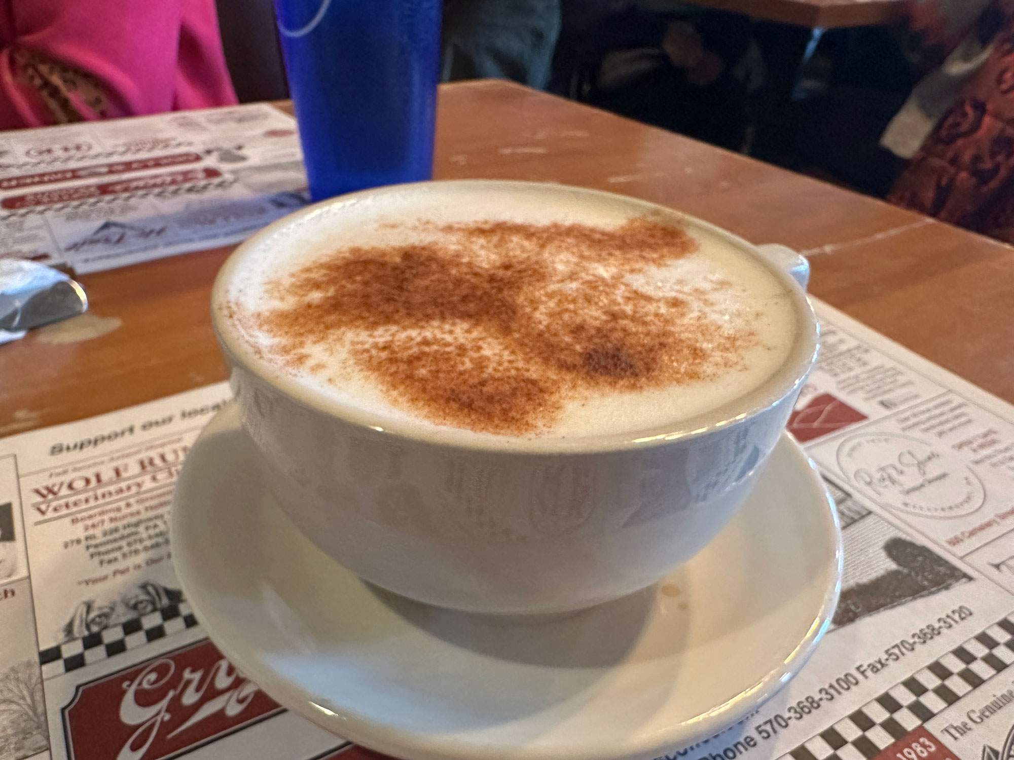 white mug filled with light gray tea drink topped with cinnamon