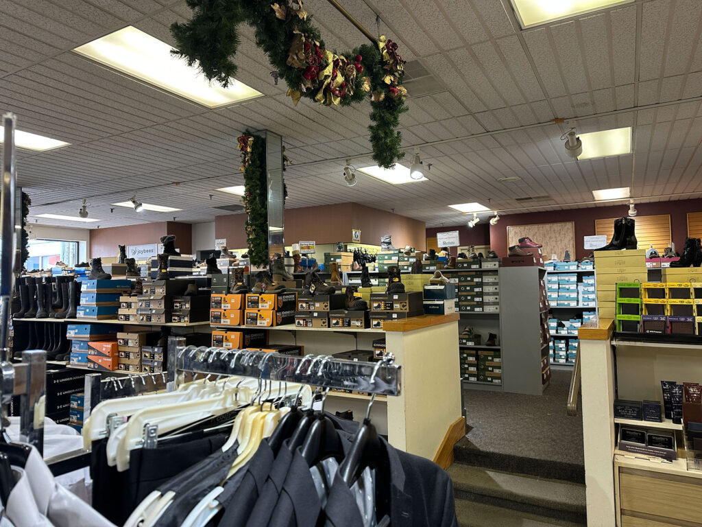 a rack of men's suit coats in the foreground with boxes of shoes on stacks in the background at Dunham's Department Store in Wellsboro, PA