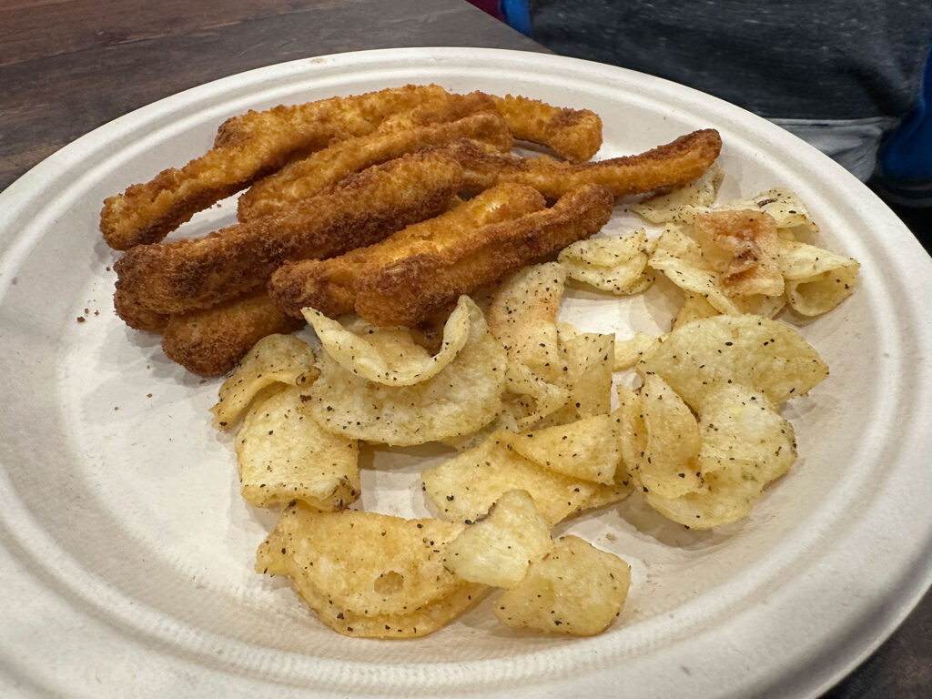 plate with chicken fries and potato chips with black pepper