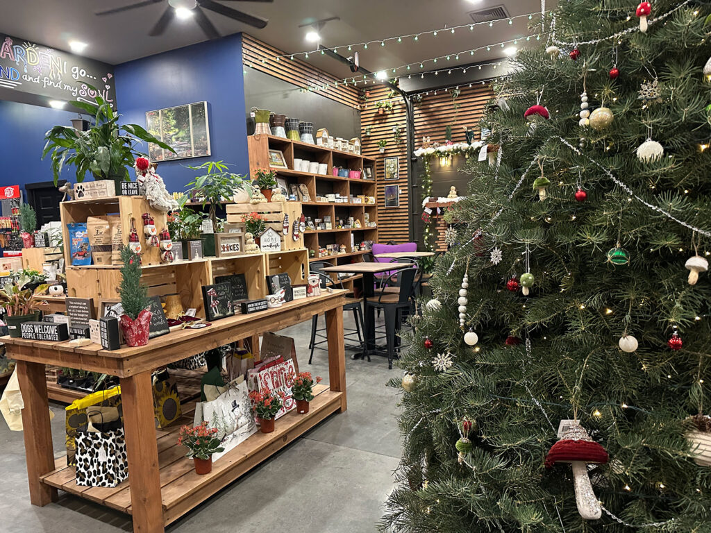 large Christmas tree on the right with a wooden table filled with holiday trinkets on the left at Hume's Blooms in Wellsboro, PA