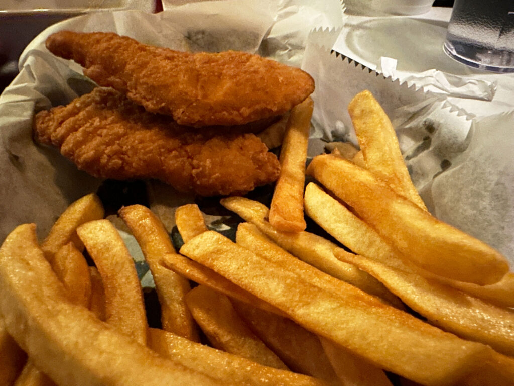 food basket lined with paper with two chicken fingers and a handful of fries