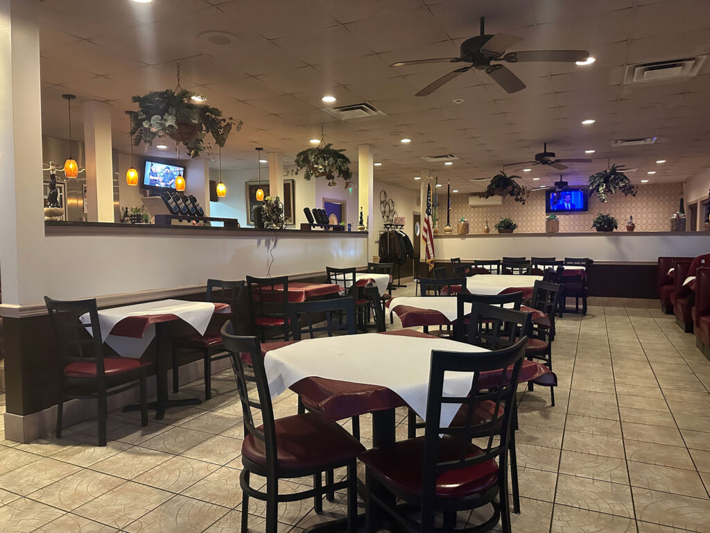 dining room filled with tables covered in dark red tablecloths topped with white paper squares