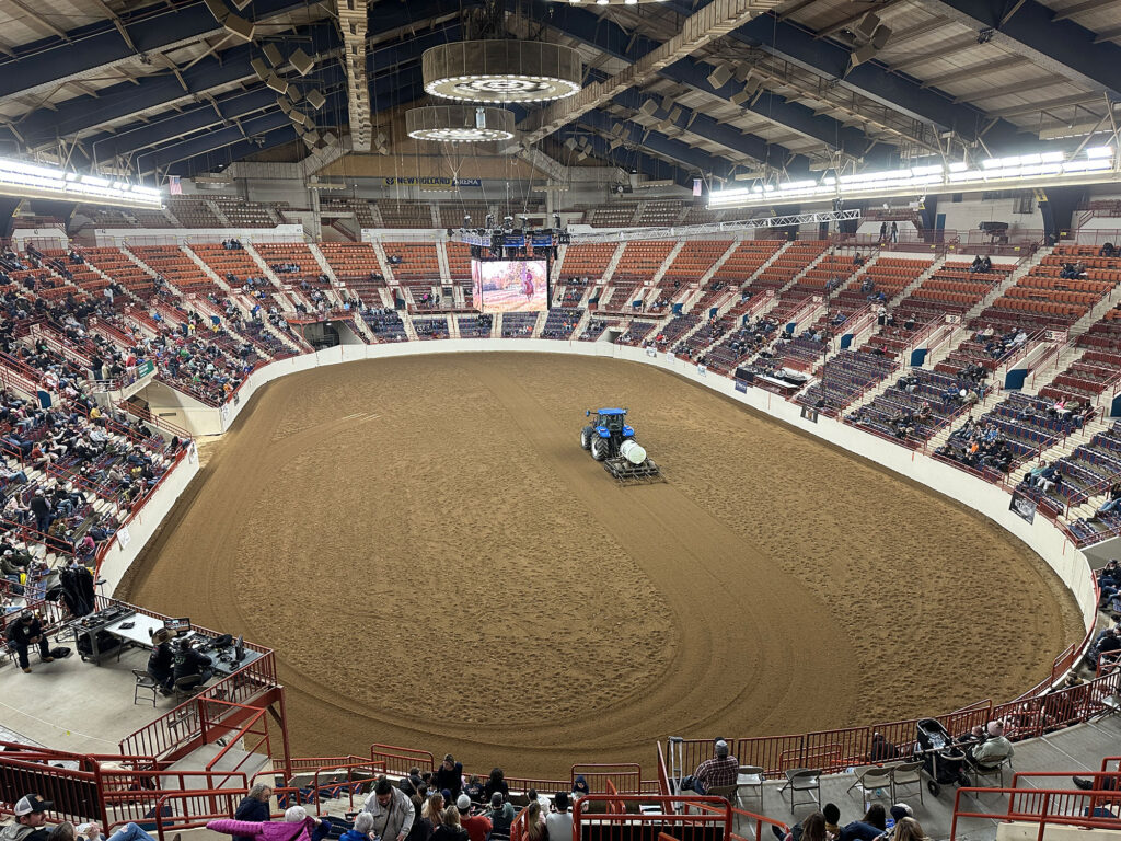 tractor dragging the dirt inside a large indoor rodeo arena