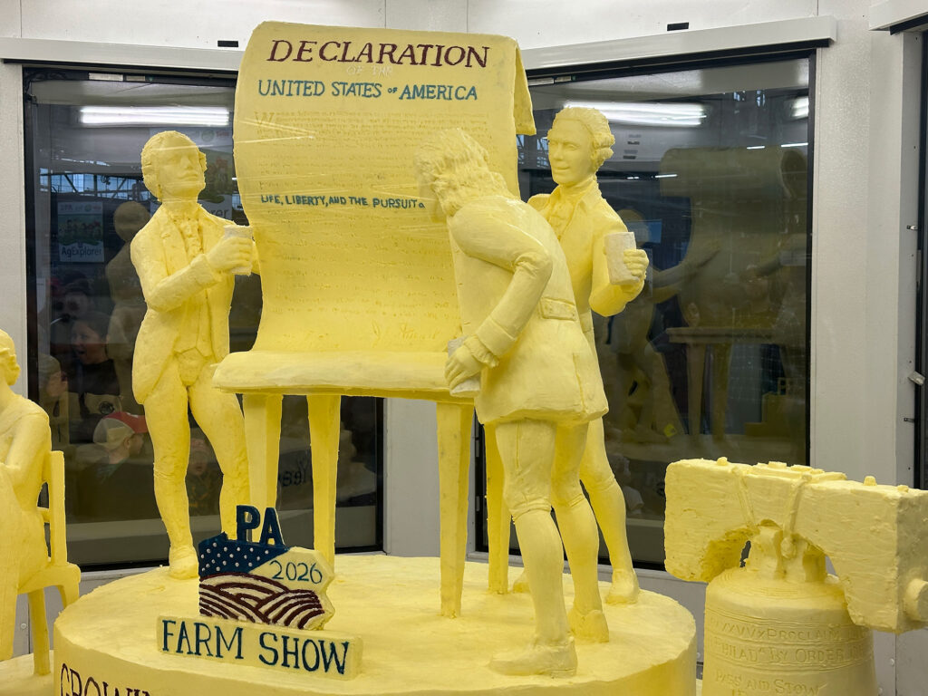 scultupre made of yellow butter depicting three founding fathers signing the Declaration of Independence.